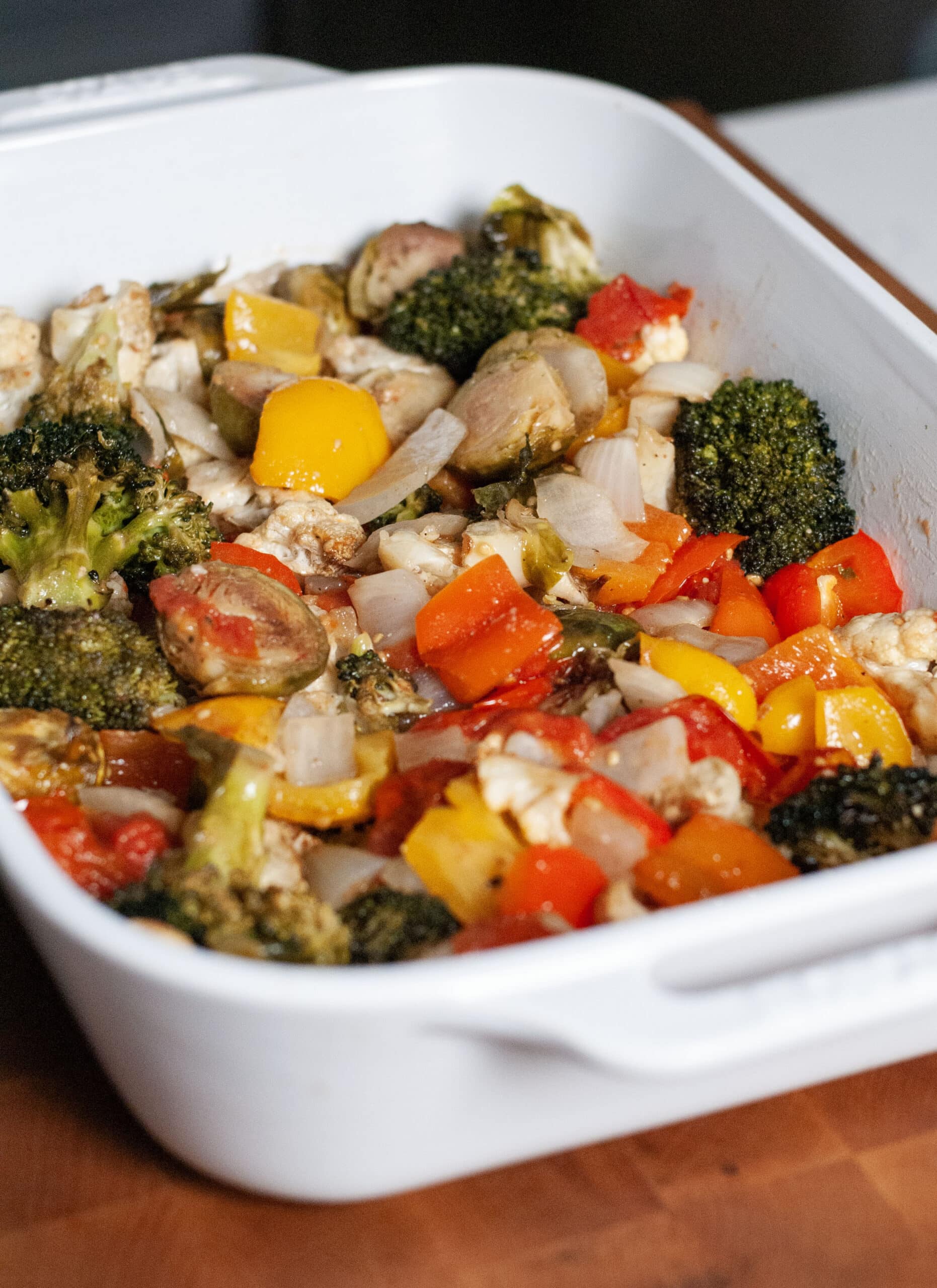 Roasted broccoli peppers and onions in a baking dish.