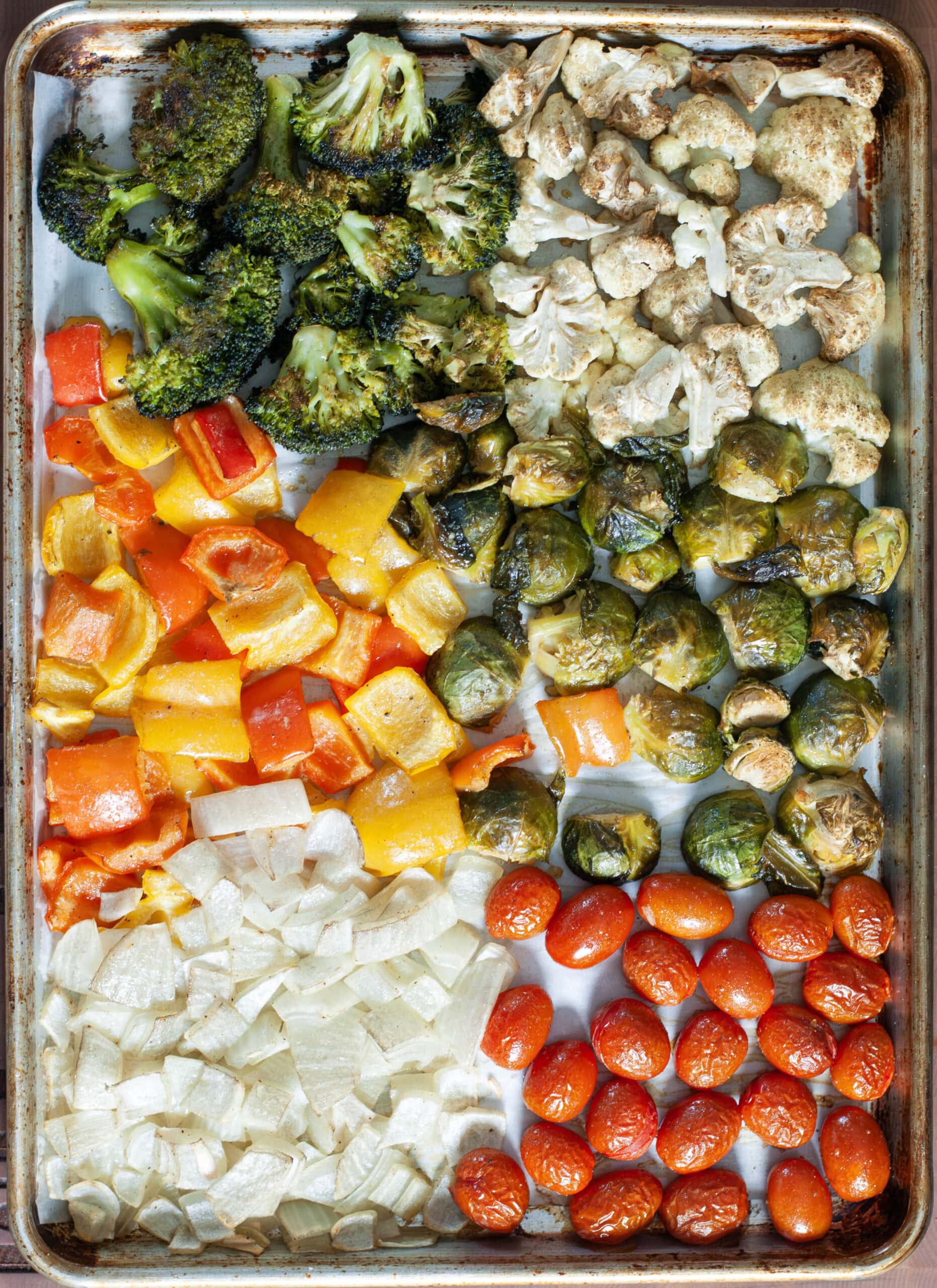 Roasted vegetables on a sheet pan with parchment paper.