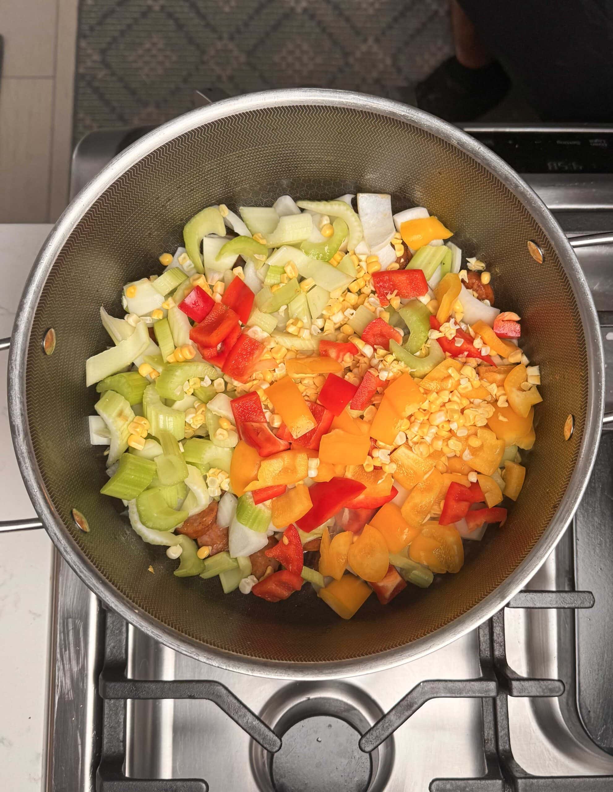 Peppers, onion, corn and celery in a pot.