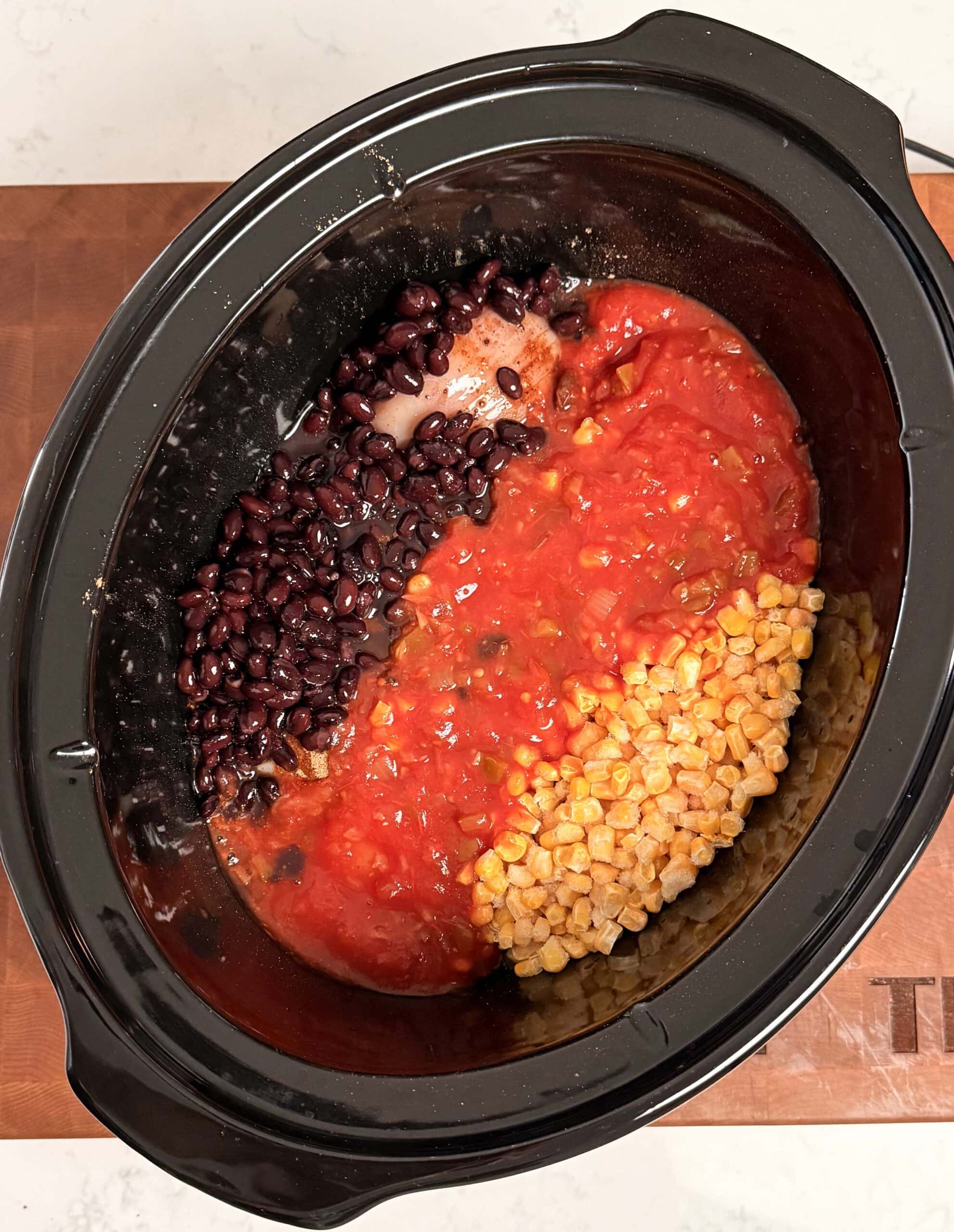 Chicken, salsa, corn and beans in a crockpot.