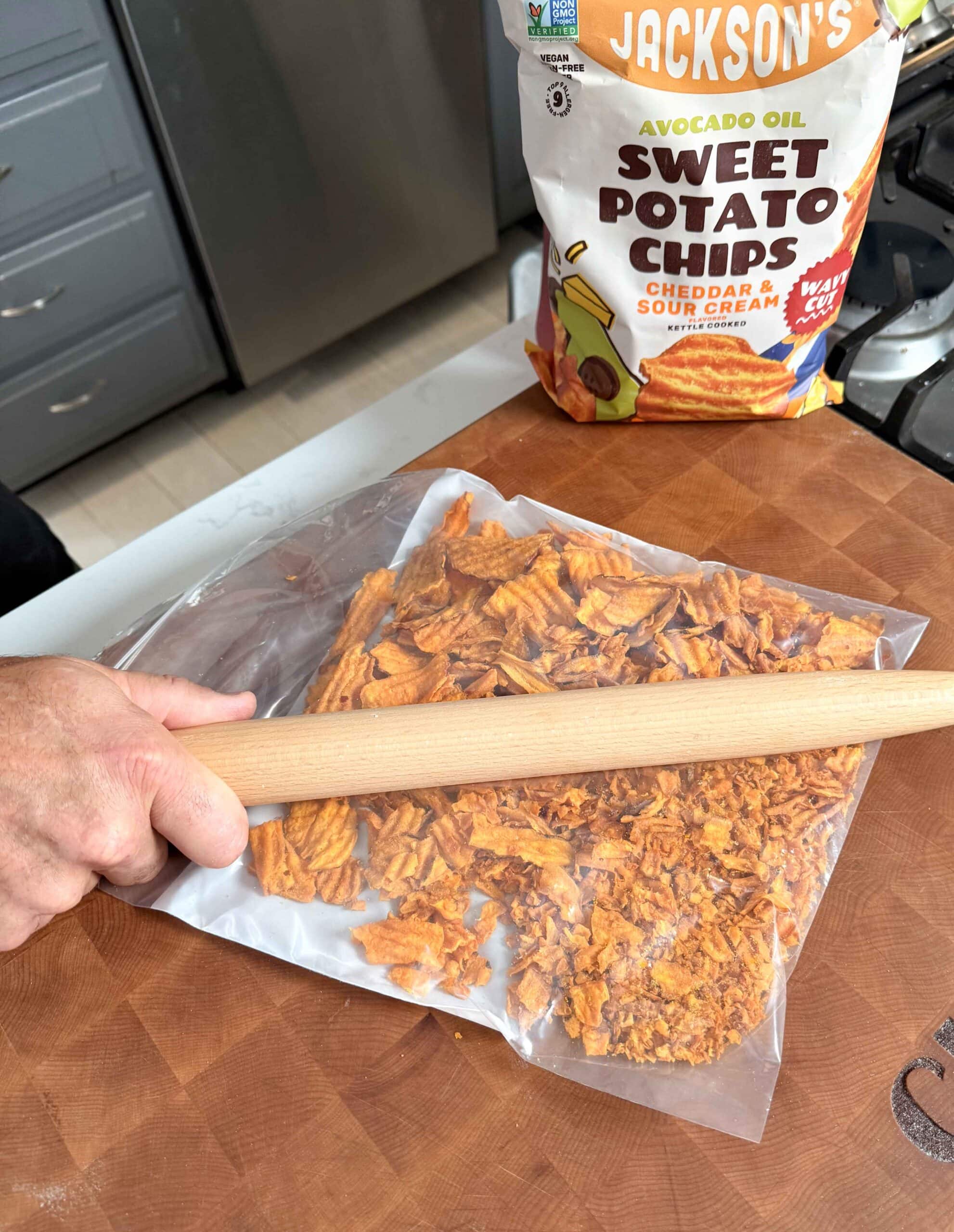 Potato chips being crushed with a rolling pin.