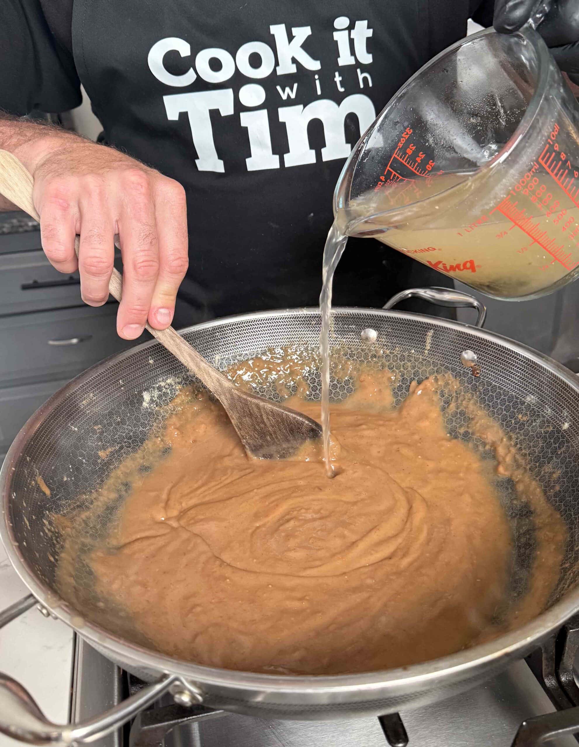 Seafood broth going into the roux mixture.