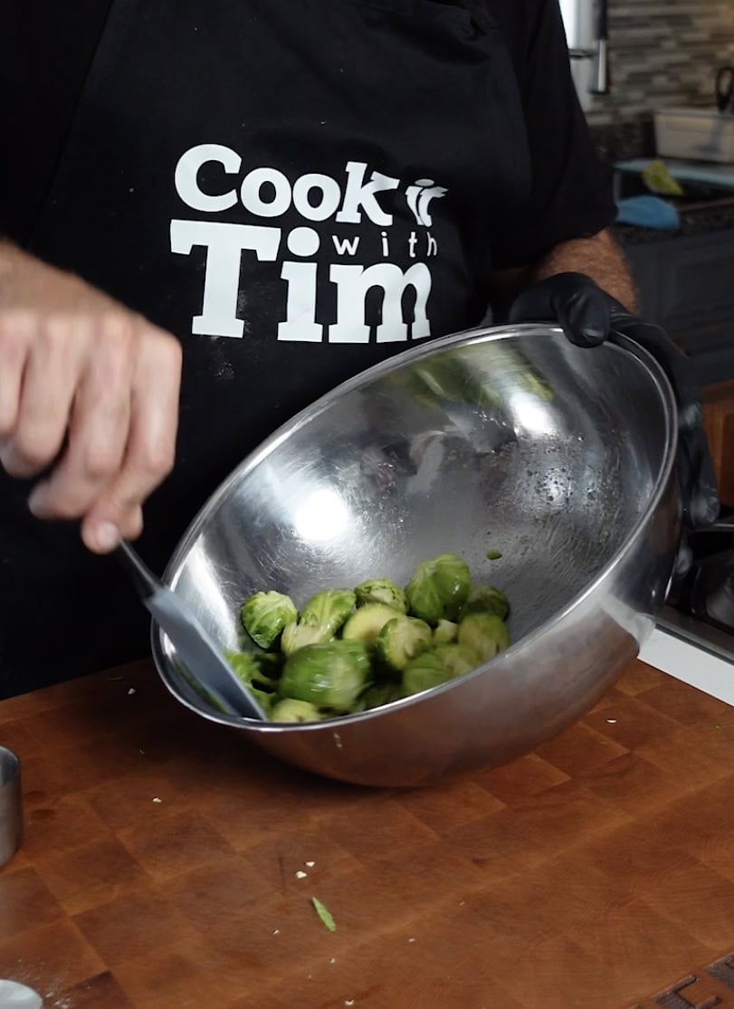 Seasoning brussel sprouts in a mixing bowl.