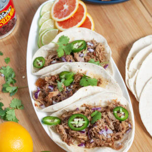 Pulled pork on tacos with cilantro and jalapeño.
