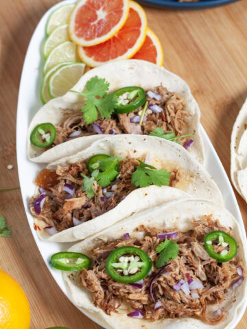 Pulled pork on tacos with cilantro and jalapeño.