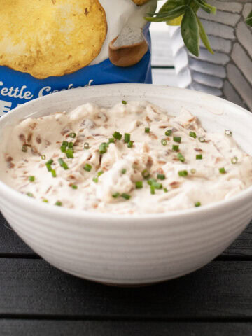 A bowl of French onion dip with kettle chips.