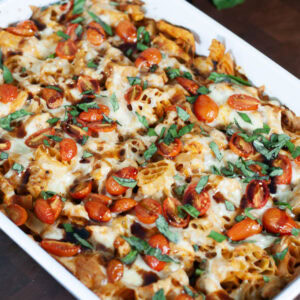 A casserole with pasta, chicken, tomatoes and basil.