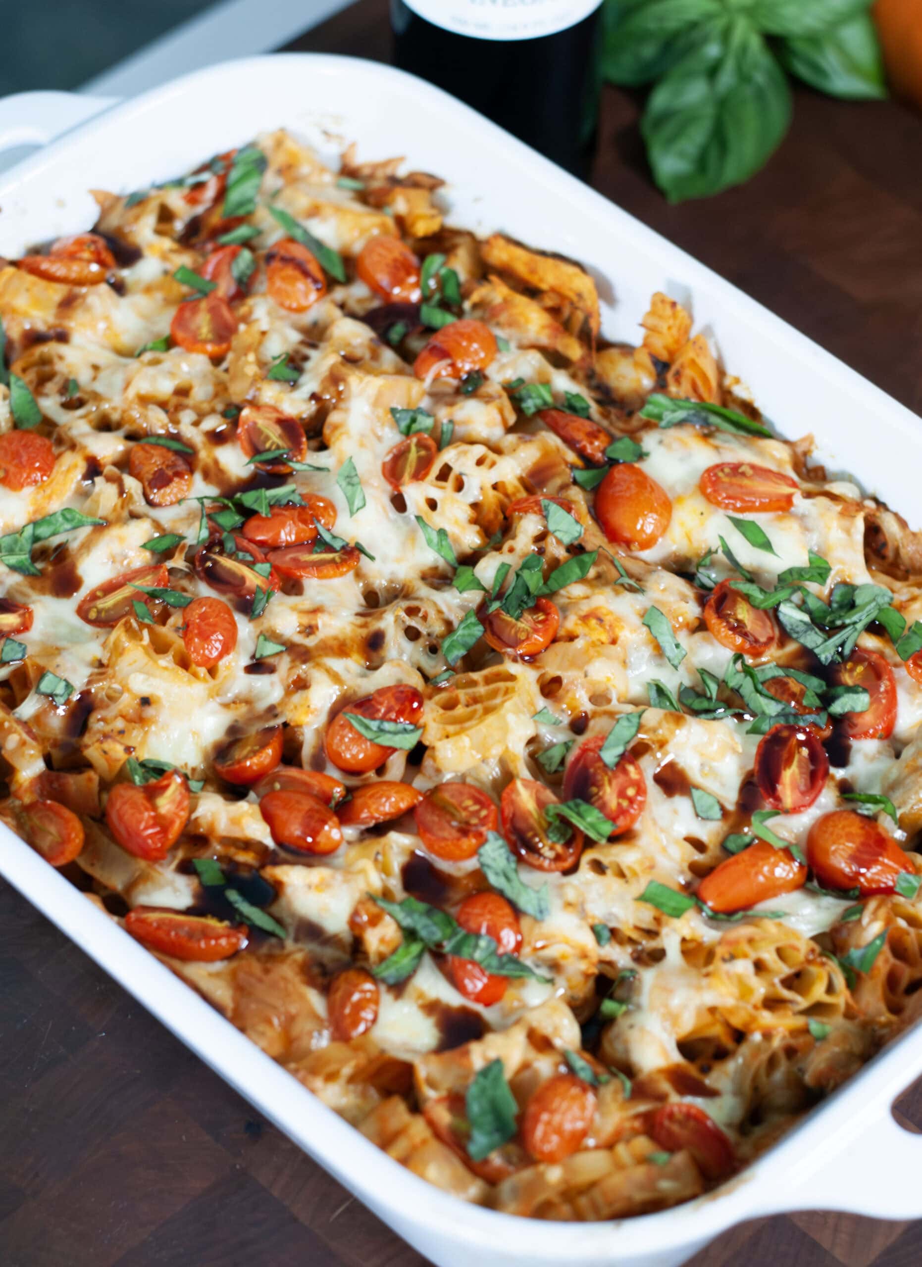 A casserole with pasta, chicken, tomatoes and basil.