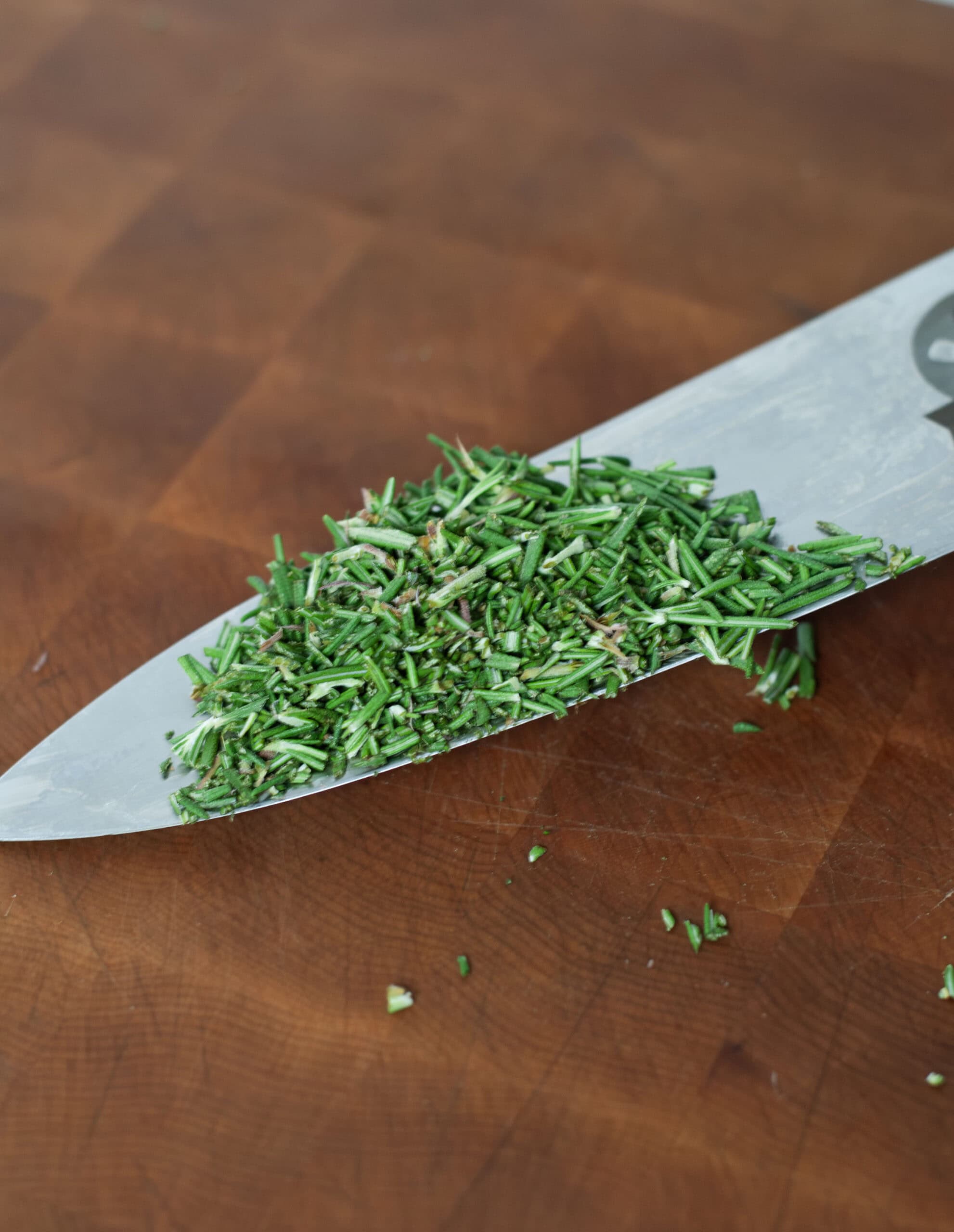 Chopped rosemary on a knife.