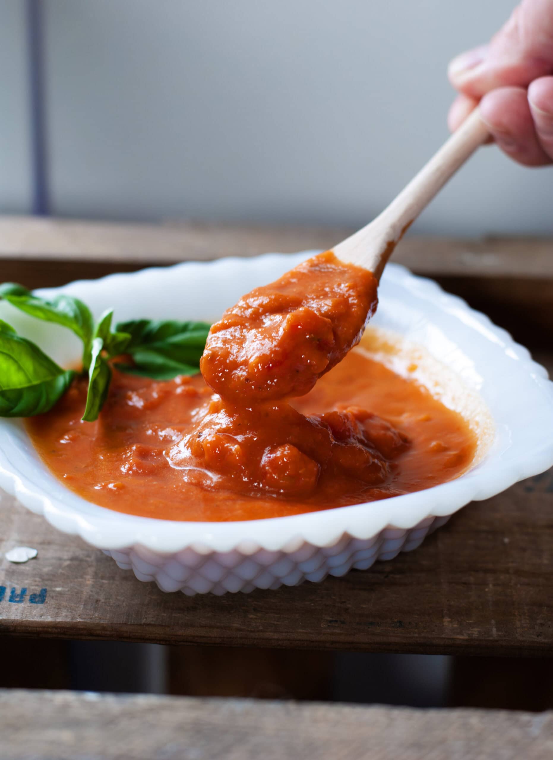 A scoop of tomato sauce with a wooden spoon.