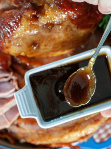 A spoon full of maple ham glaze over a ham.
