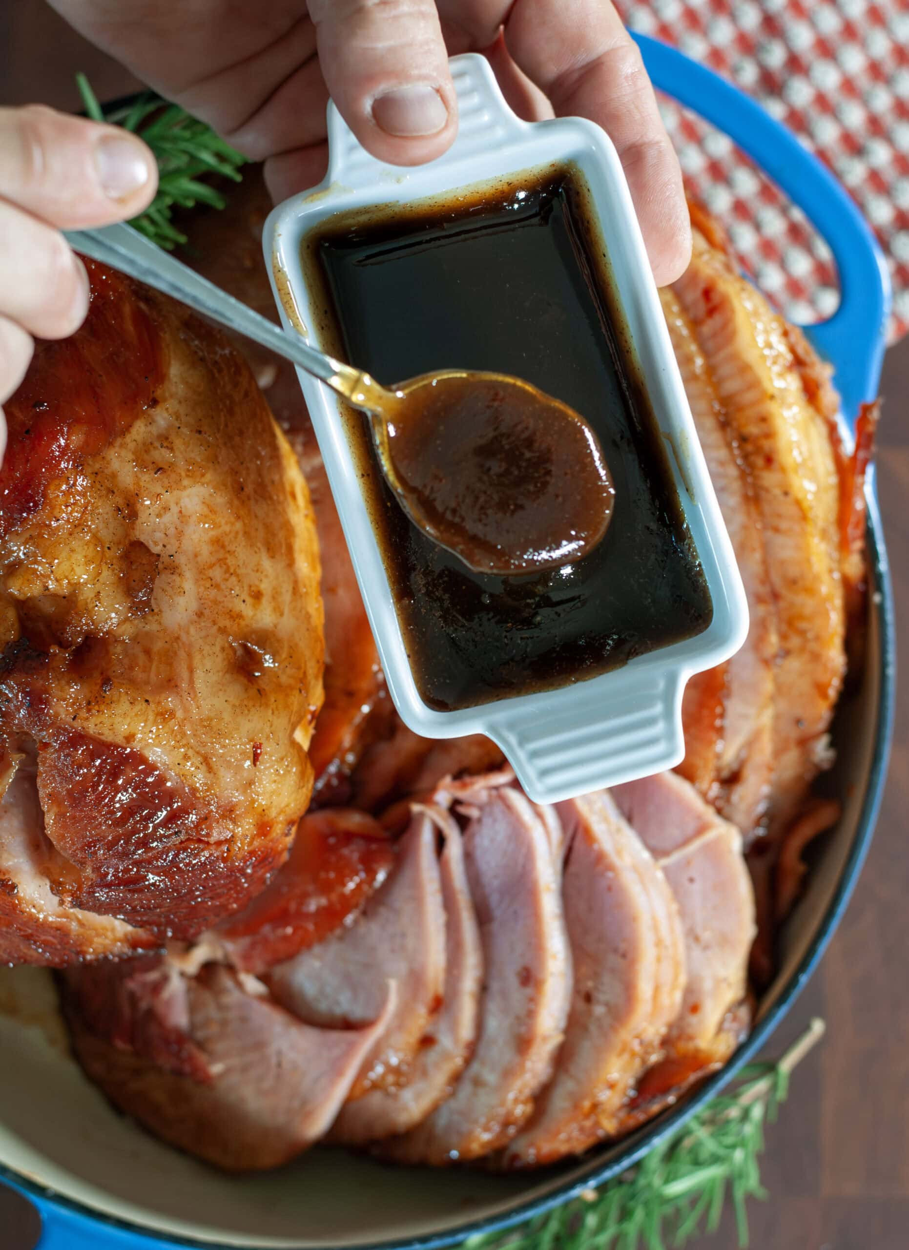 A spoon full of maple ham glaze over a ham.