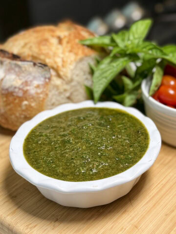 Basil Pesto in a bowl with bread and tomatoes.