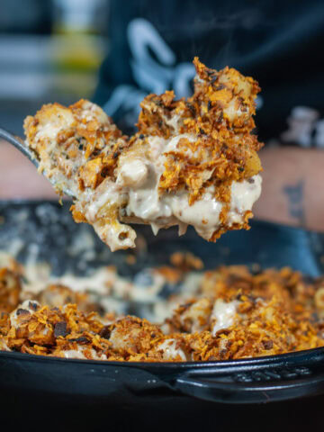 A scoop of cheesy spicy Mac and cheese over a black skillet.