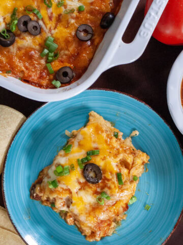 A slice of turkey casserole on a blue plate with tortillas.