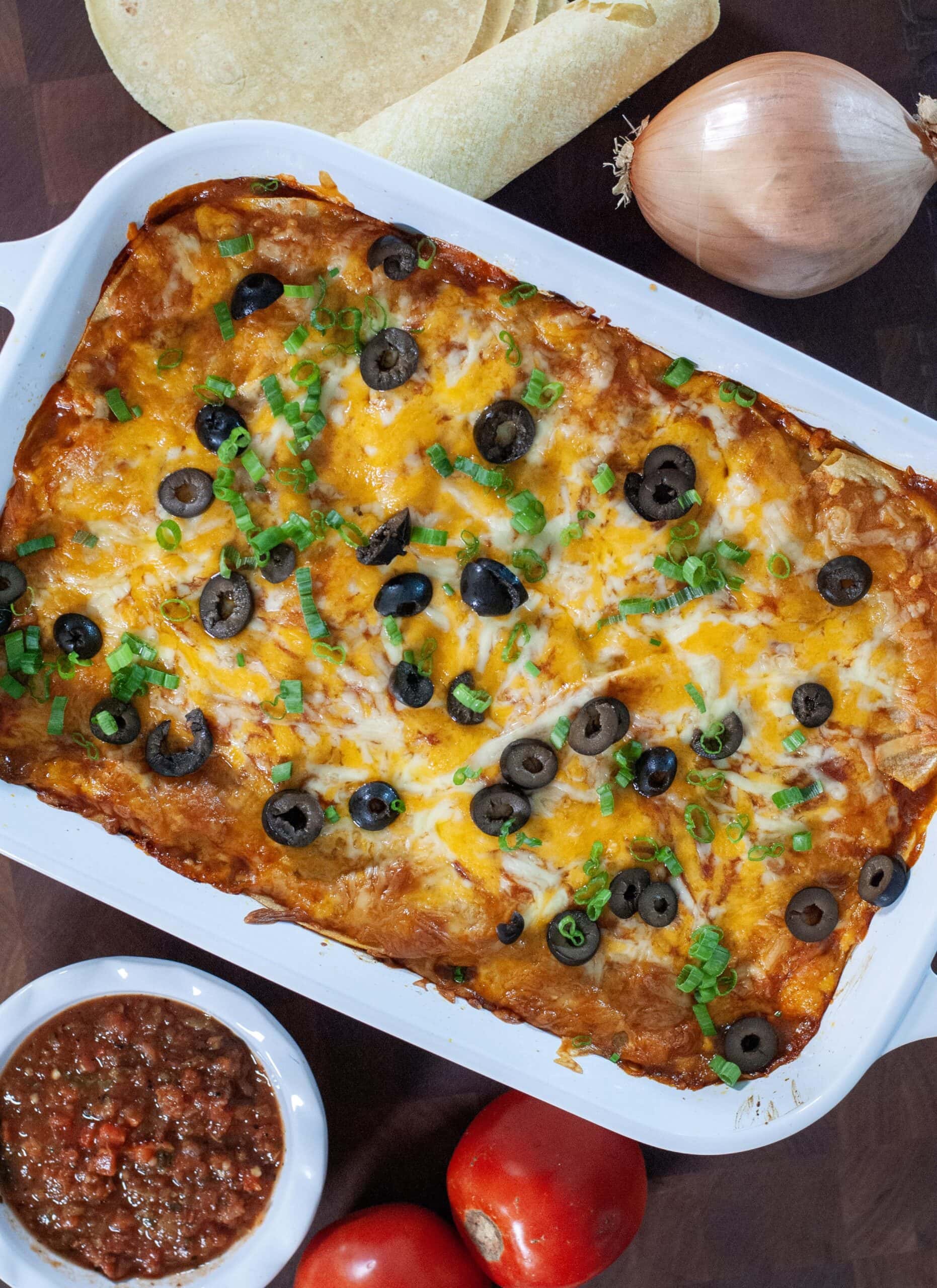 A colorful baked casserole with black olives and green onions.