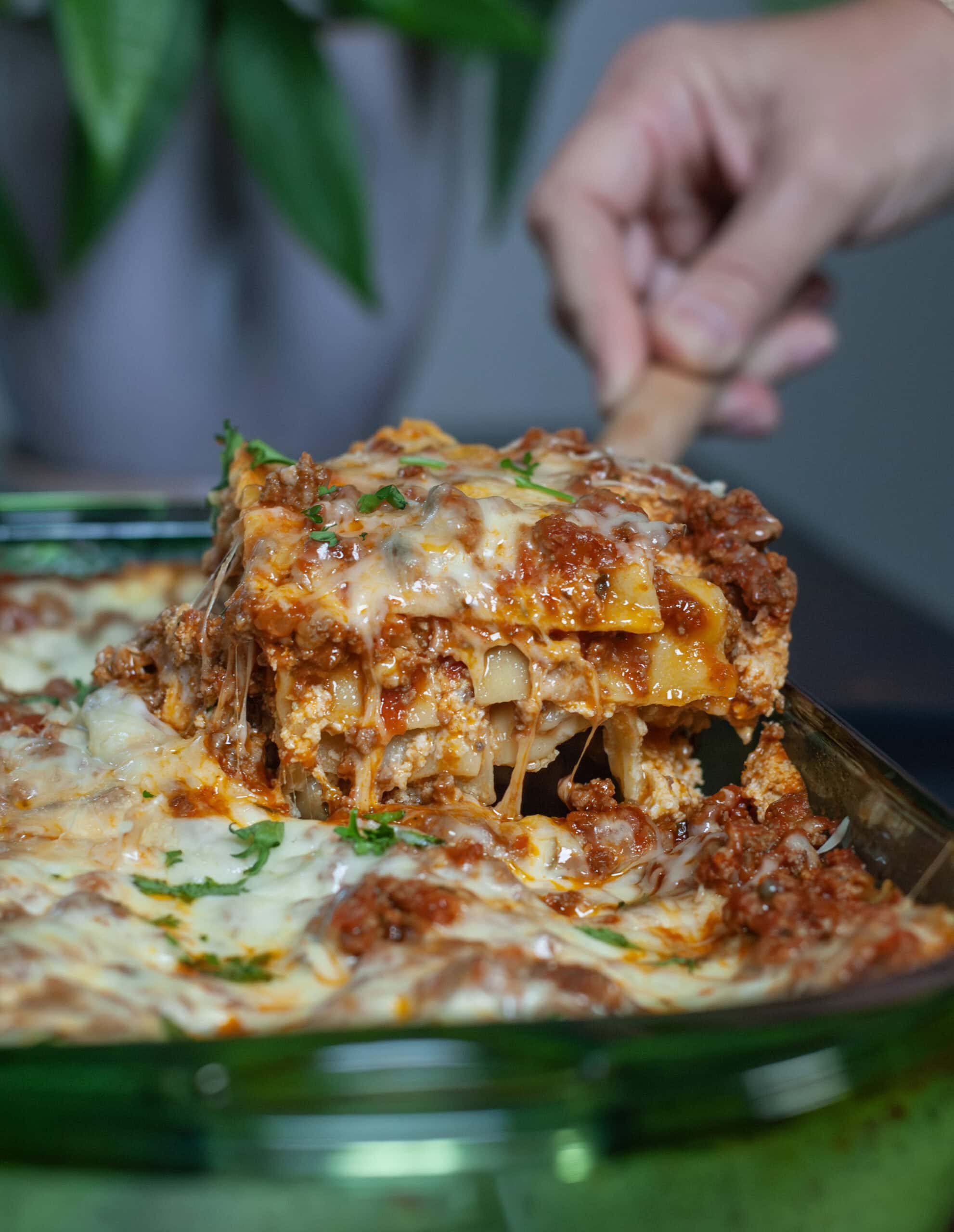 A scoop of lasagna cheese coming out of a baking dish.
