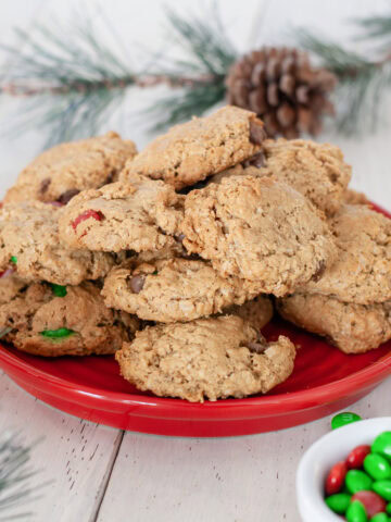 Monster cookie stacked on a red plate next to M&Ms.