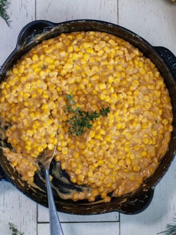 An overhead view of creamy skillet corn next to thyme.
