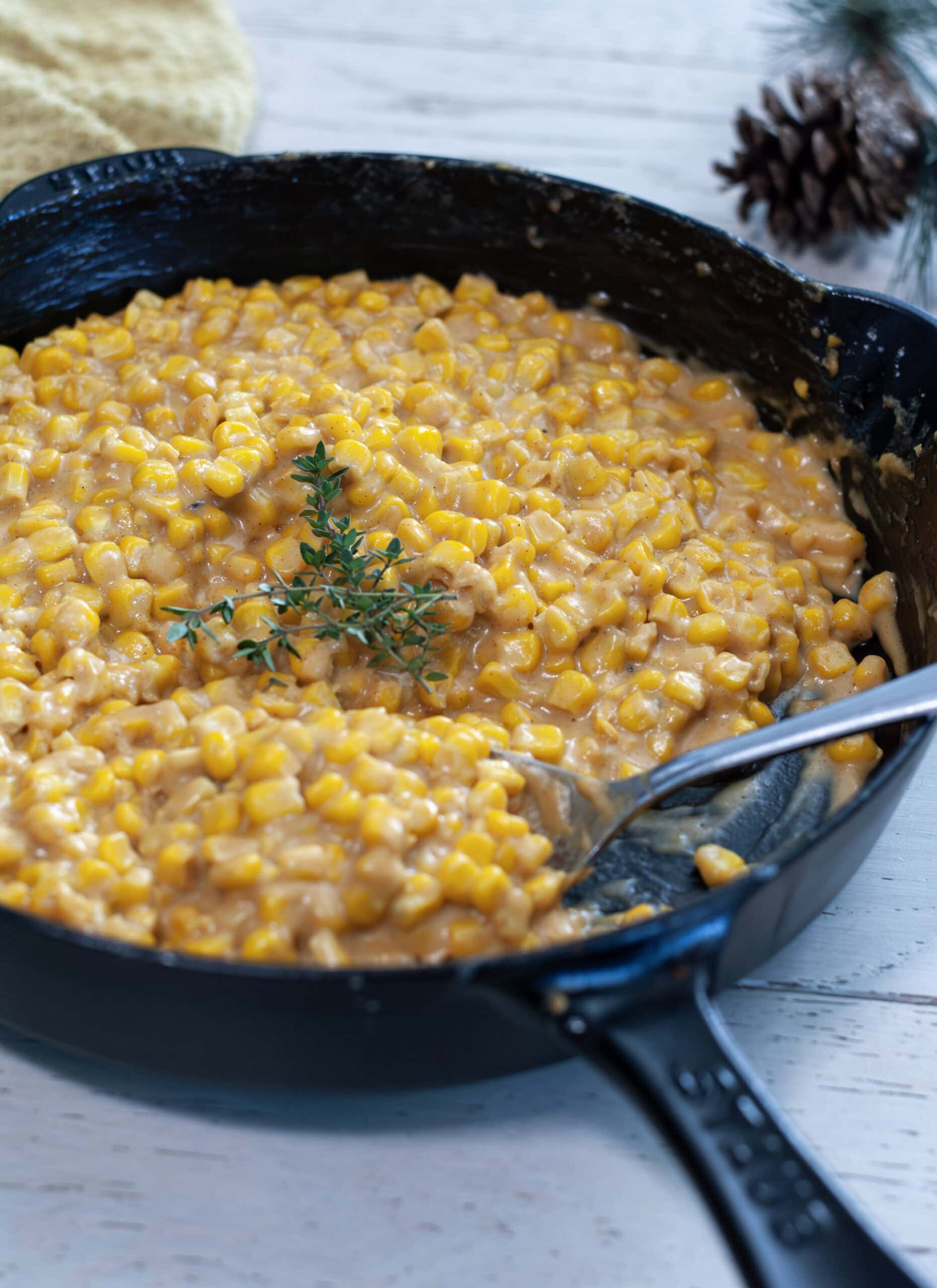 Creamy skillet corn in a cast iron skillet with a spoon.