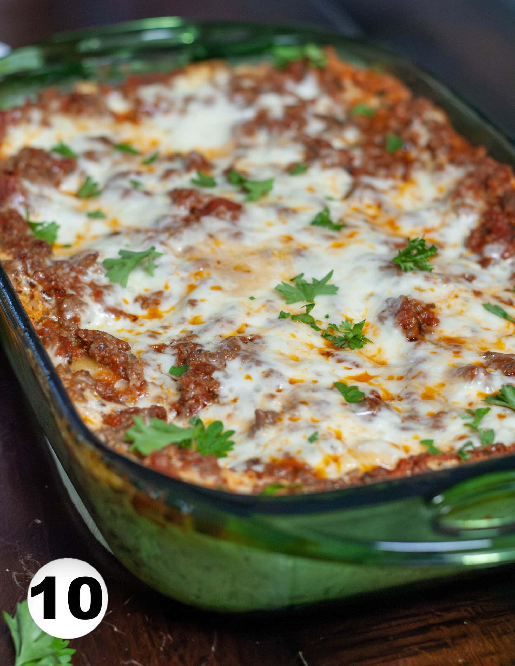Cooked lasagna topped with cheese and parsley.