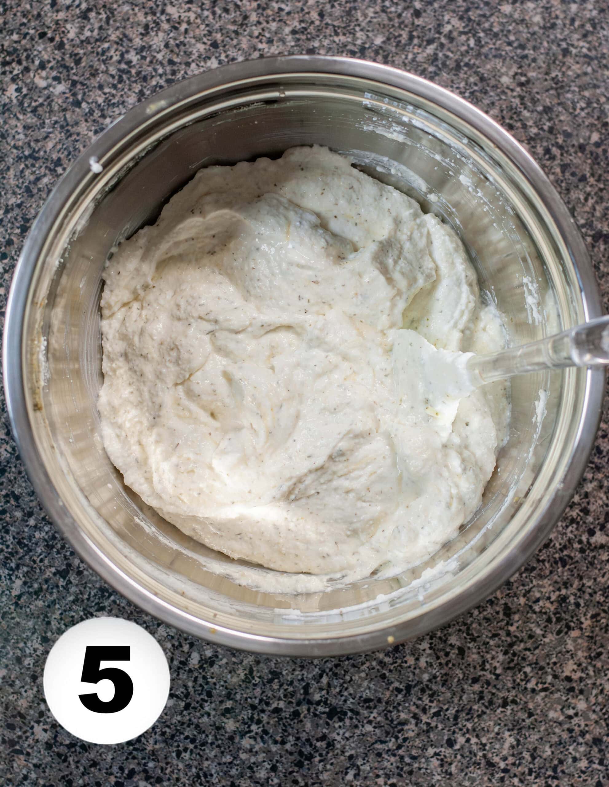 A mixing bowl full of cottage cheese mixture for lasagna.