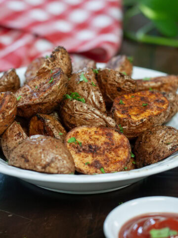 Roasted red potatoes in a dish next to ketchup.
