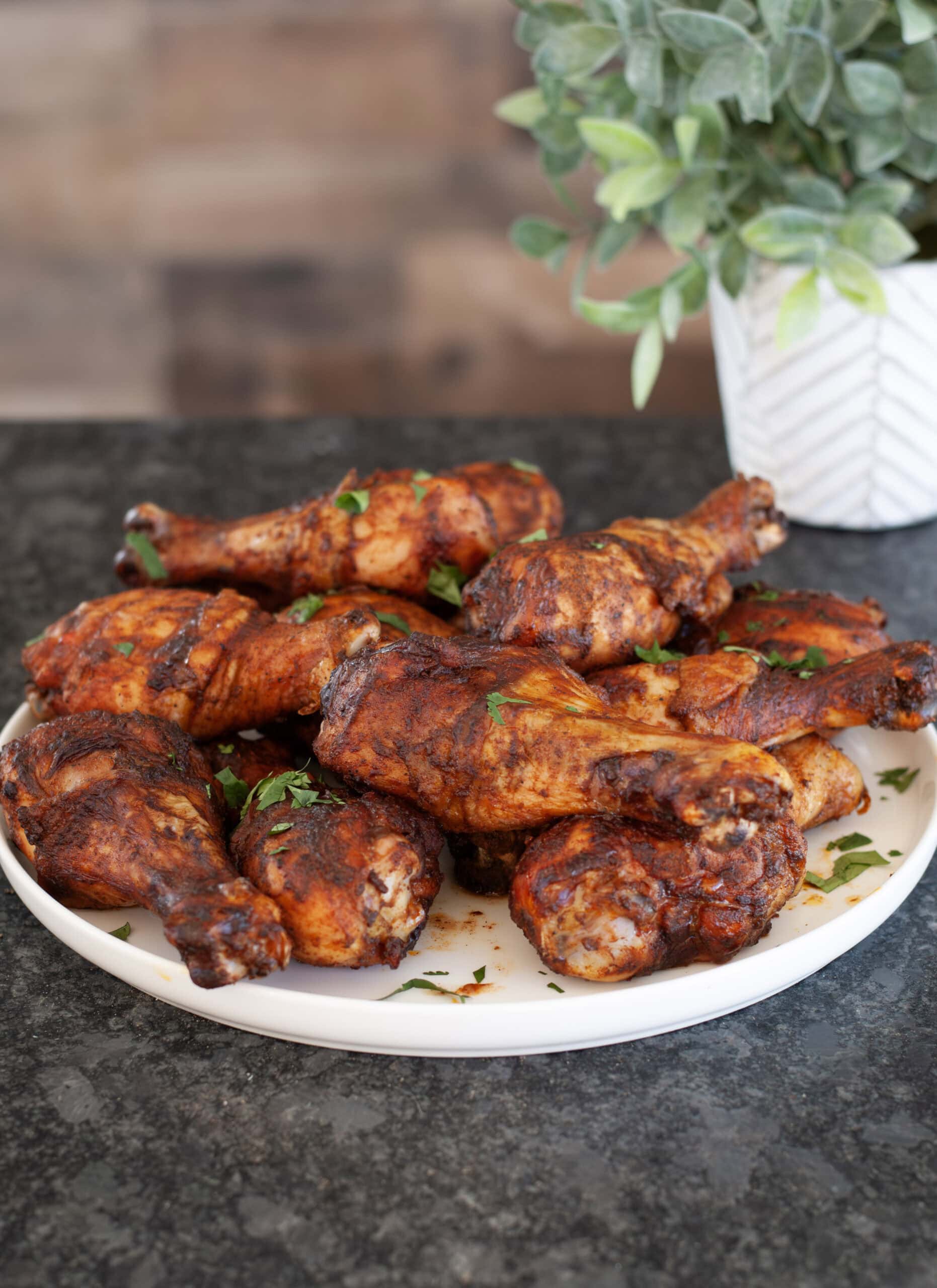 Chicken legs piled high on a white plate.