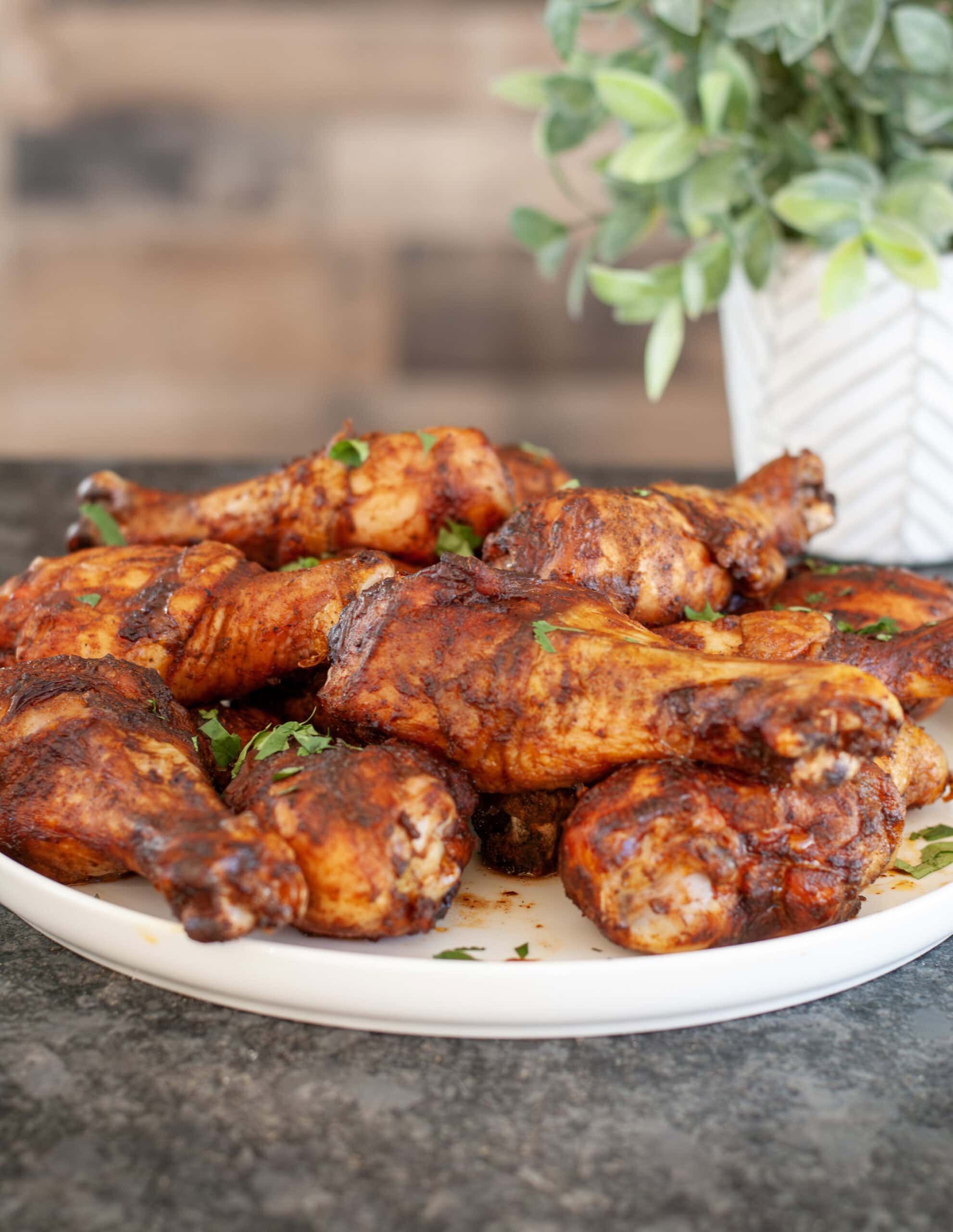 Baked chicken legs with parsley on a white plate.