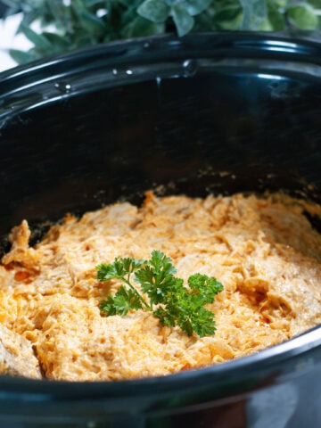 Buffalo chicken dip in a slow cooker topped with parsley.