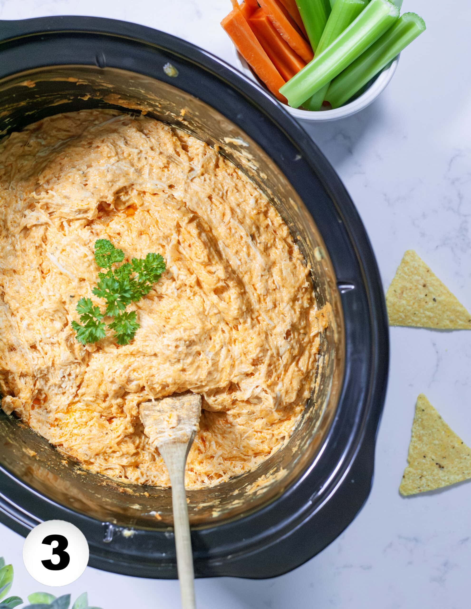 Buffalo Chicken Dip in a slow cooker with a serving spoon.