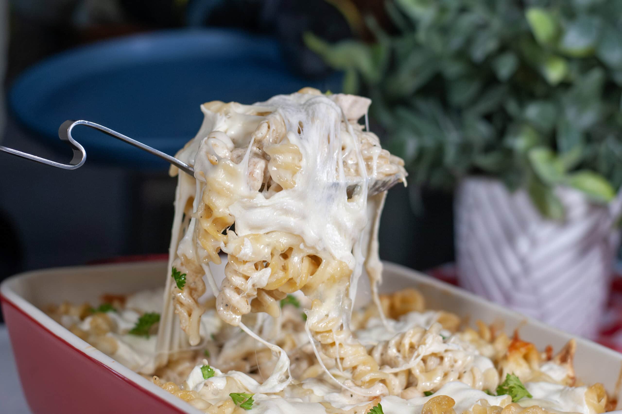 A cheesy scoop of mozzarella and chicken over a baking dish.