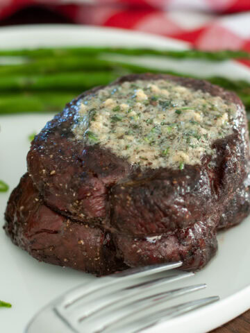 A steak filet topped with melted rosemary compound butter.