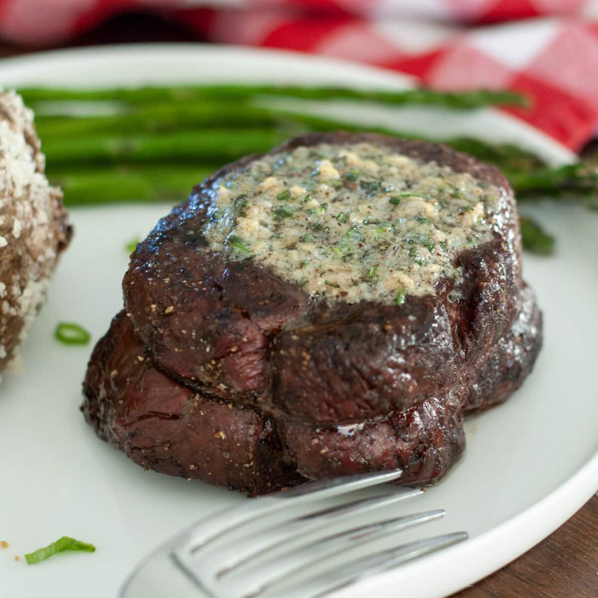 A steak filet topped with melted rosemary compound butter.