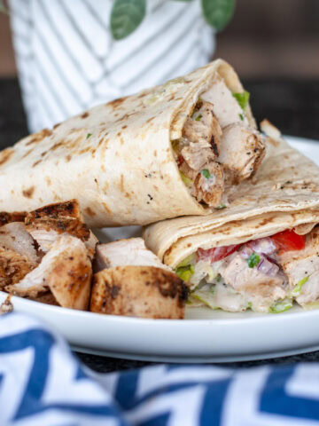 Grilled chicken in a wrap with lettuce and tomato and yogurt sauce.