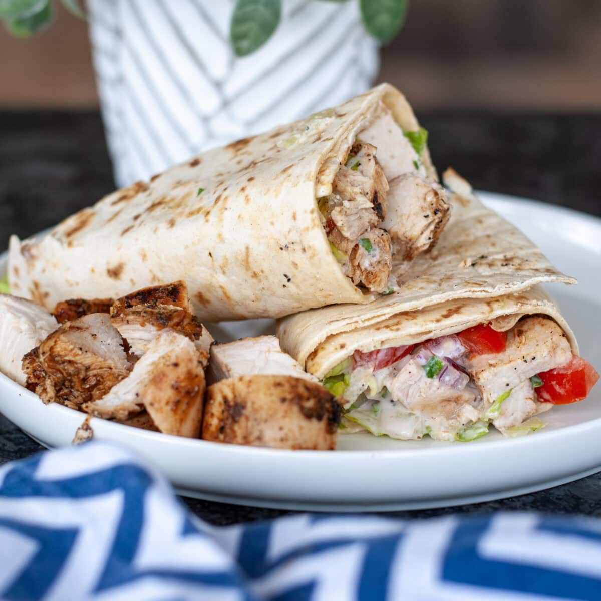 Grilled chicken in a wrap with lettuce and tomato and yogurt sauce.
