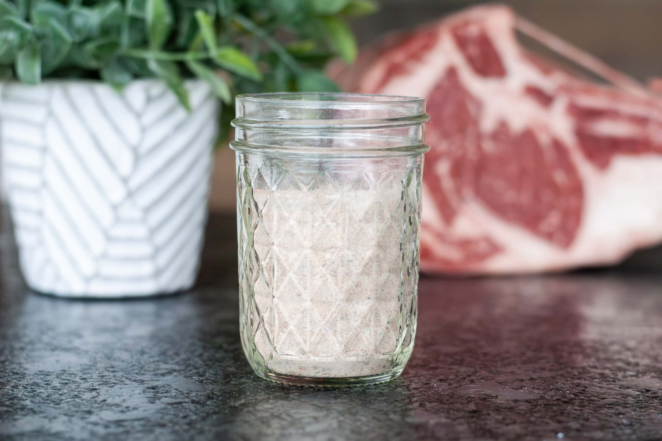 Prime rib seasoning in a cup next to a ribeye roast.