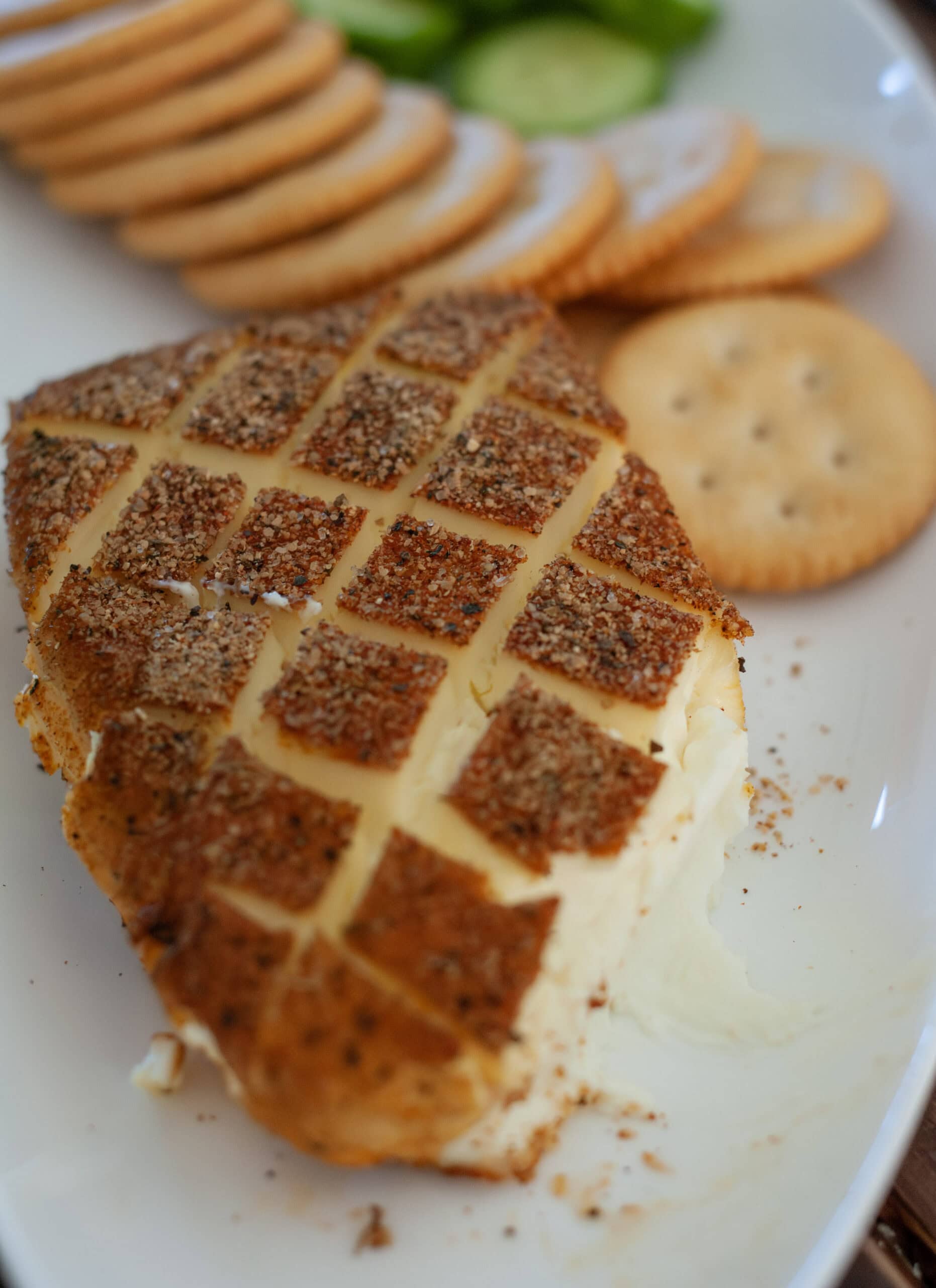 Cream cheese on a plate with crackers and cucumbers.