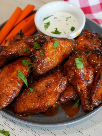 Chicken wings on a plate with chives and ranch.