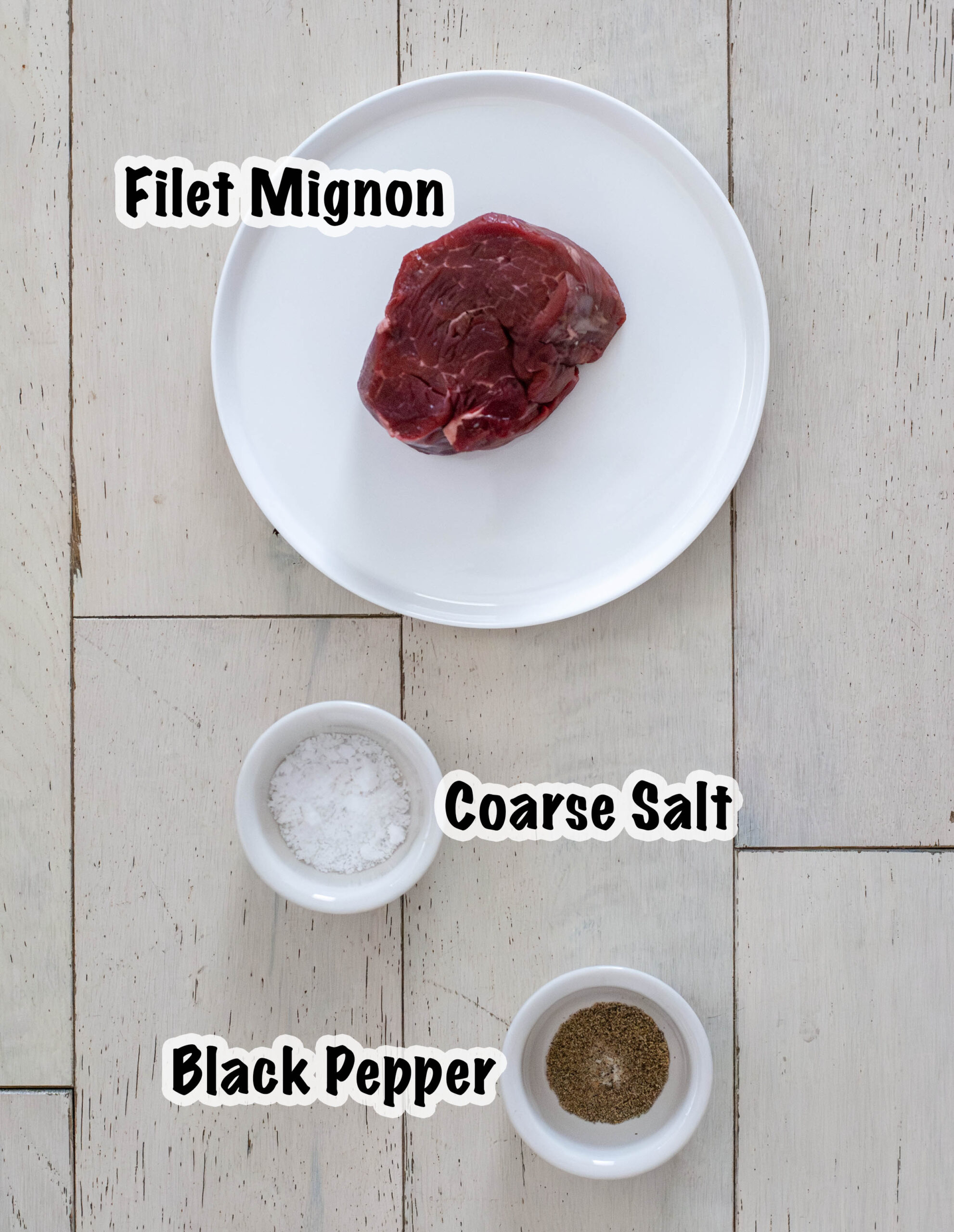 A cup of salt, a cup of pepper and filet on a plate.