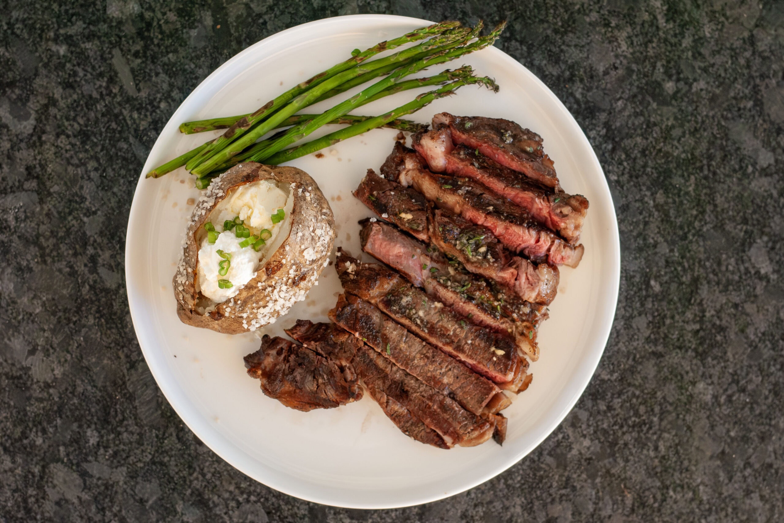 Grilled ribeye with a baked potato and grilled asparagus.