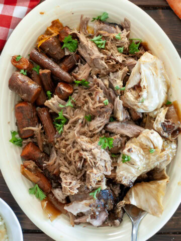 Crock Pot Pork Roast on a white plate with carrots and cabbage.