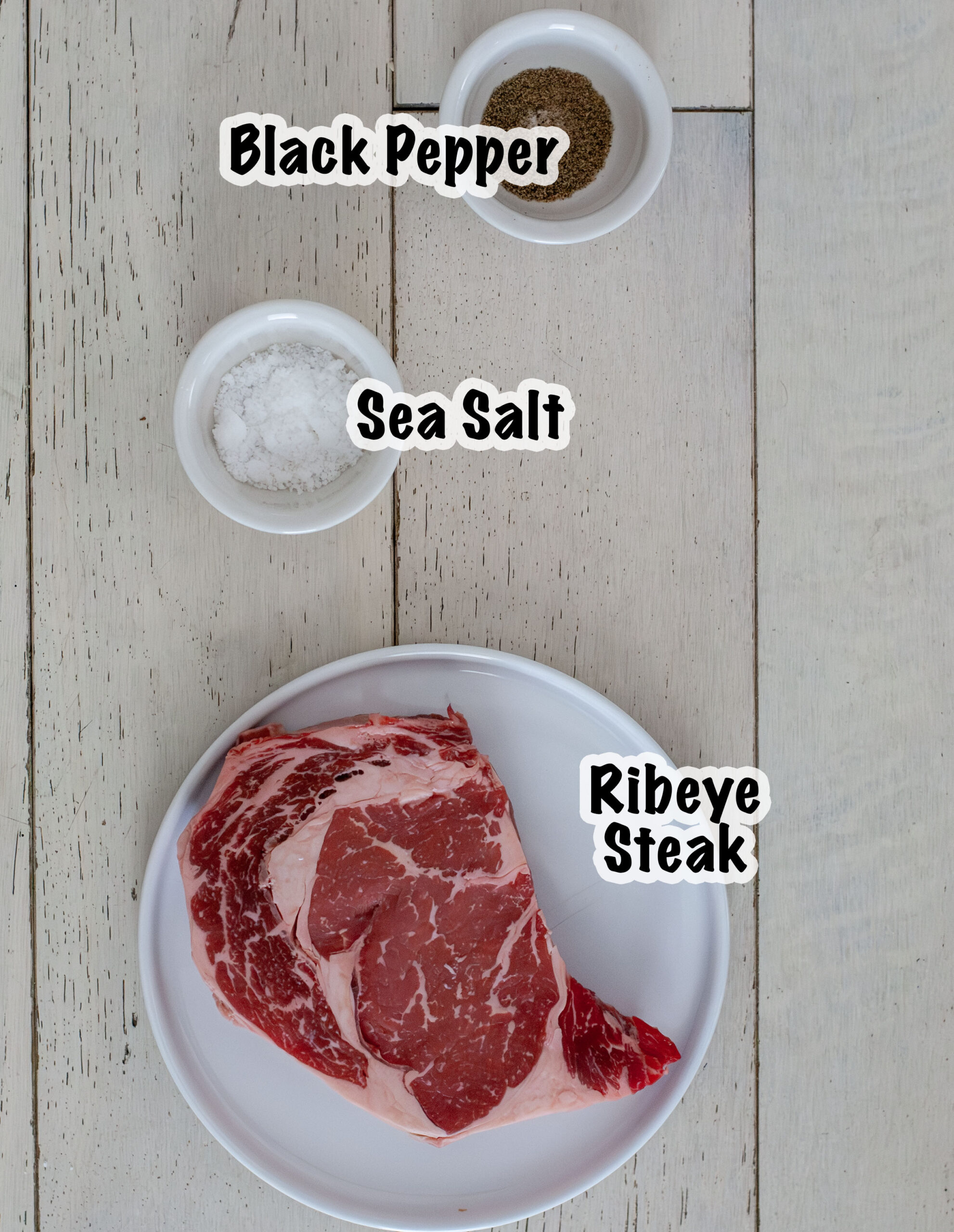 Ingredients for a ribeye steak on plates and bowls.