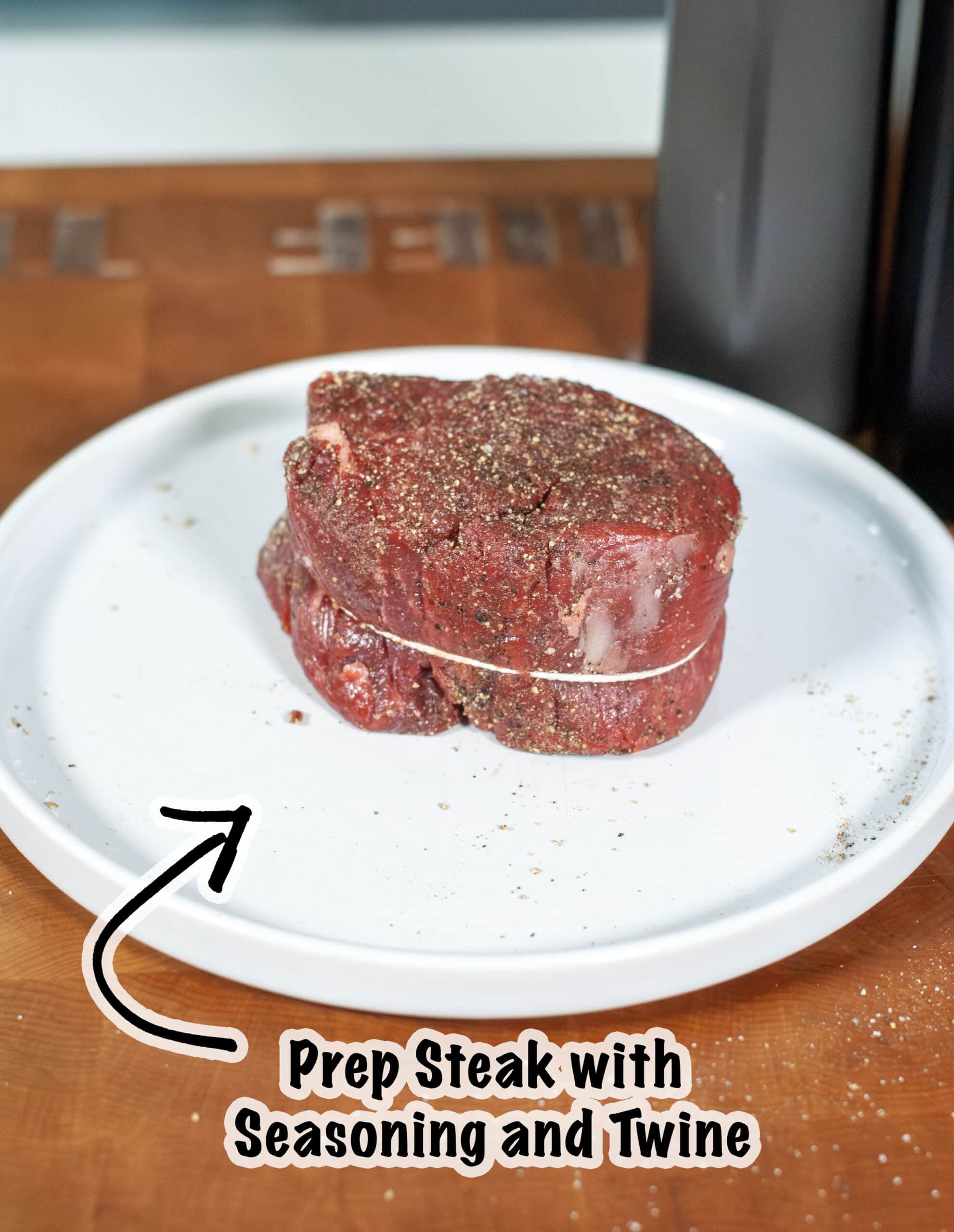 A filet mignon seasoned with salt and pepper and wrapped in twine.