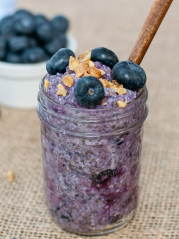 Blueberry oats in a small mason jar with a spoon.