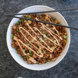 Fried rice in a bowl with sesame seeds and sauce.