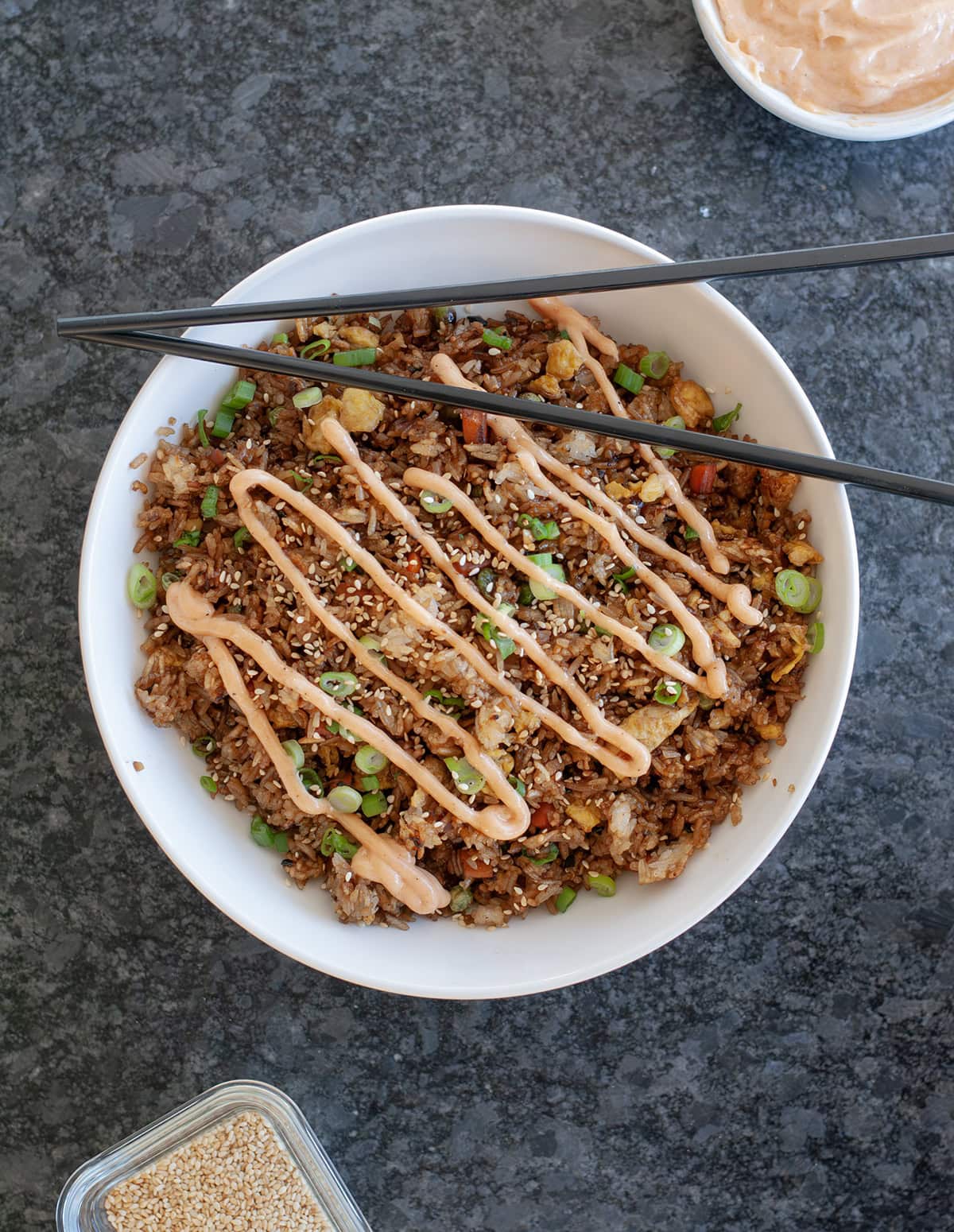 Fried rice in a bowl with sesame seeds and sauce.