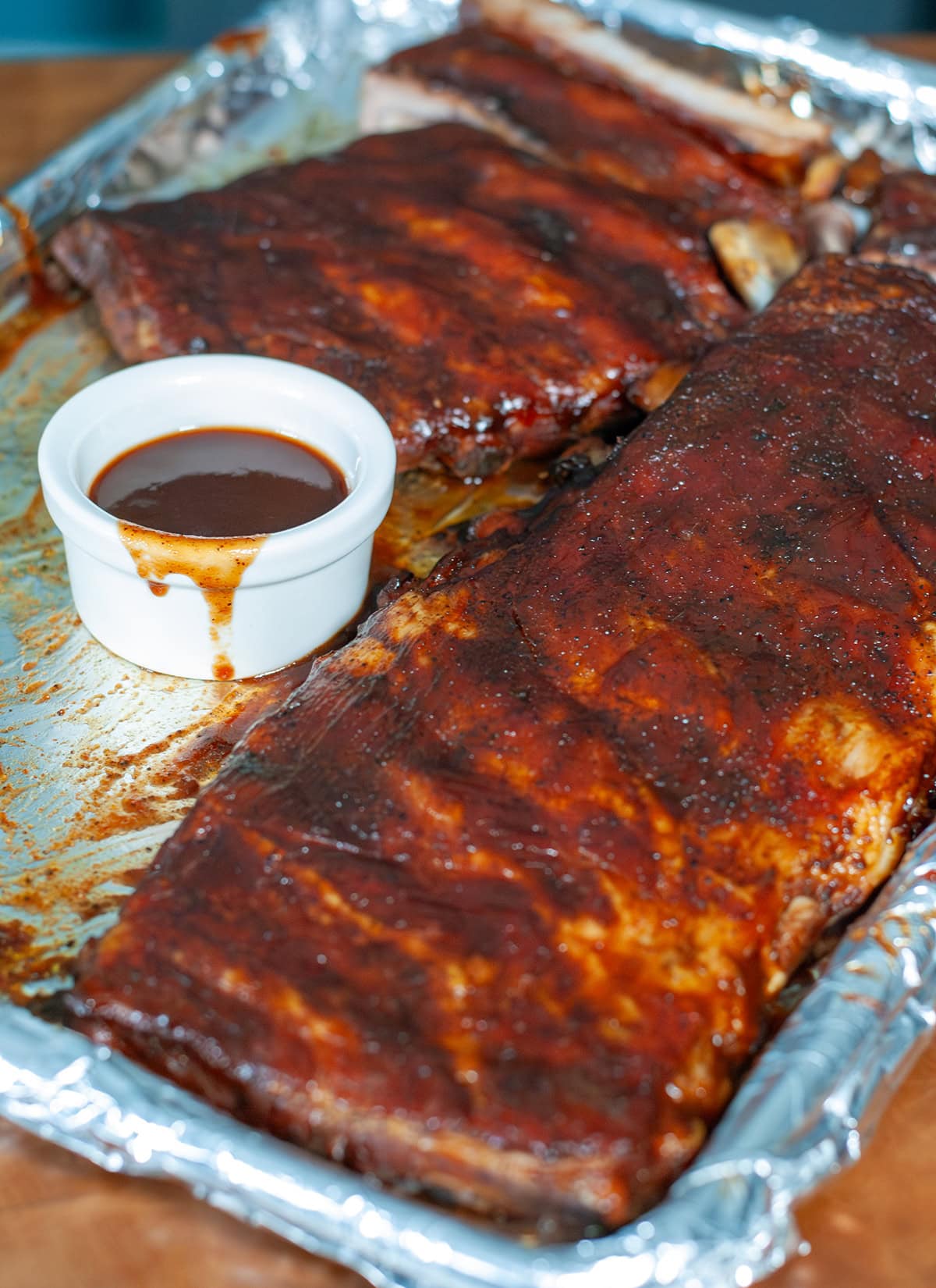 Oven baked ribs with BBQ sauce on aluminum foil.