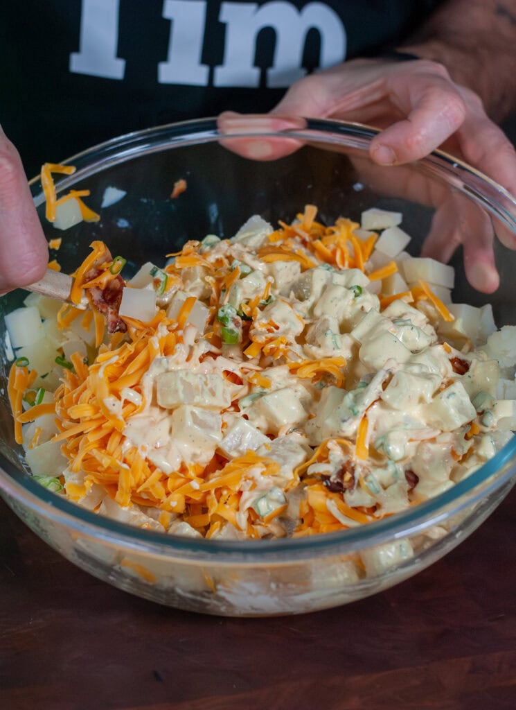 Mixing together sauce with boiled potatoes.