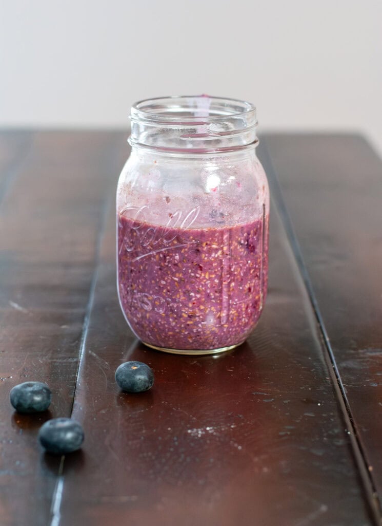 Oats mixed with blueberries in a mason jar.